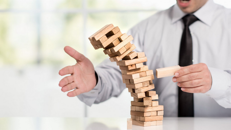 A person is playing a game of Jenga, with the tower starting to topple over.