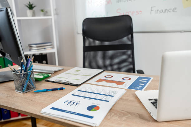 An organized office desk with business charts, documents, and a laptop for starting a travel company in Dubai, UAE.